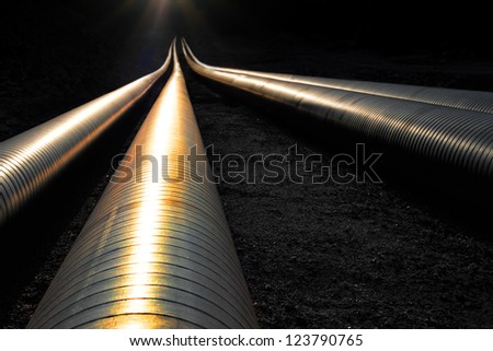 Pipelines reflecting the evening light, disappearing into darkness