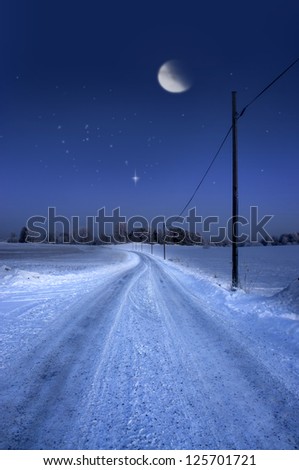 Rural dirt road in winter evening with half moon and stars in sky