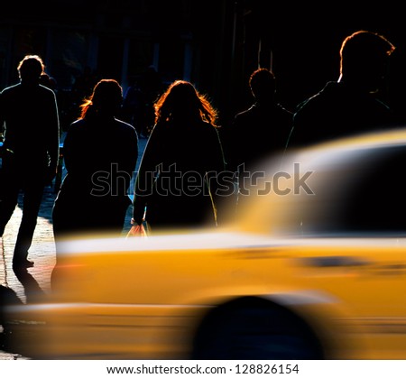 Silhouettes of people on back lit street, trying to catch a cab