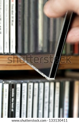 close up of man taking out CD from collection on shelf