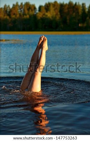 legs of swimming woman in lake in summer