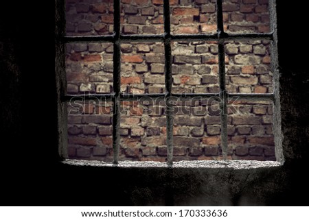 Brick wall viewed through prison window with metal bars