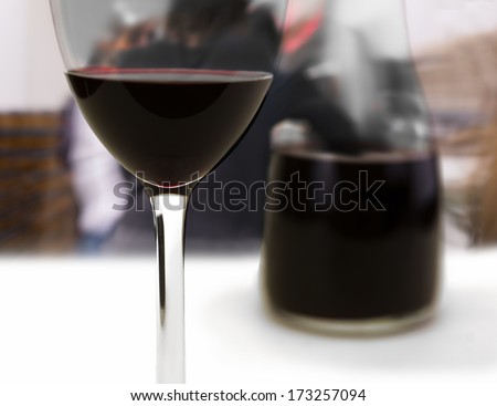 Glass of red wine with people hanging at bar in background
