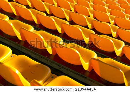 Rows of empty yellow plastic seats at sports stadium