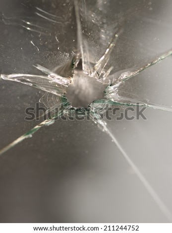 close up of smashed glass window with hole