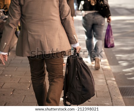 back of man in beige clothes with back packer on sidewalk