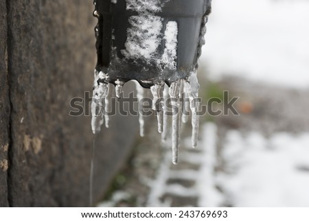 closeup of dripping icicles on draining pipe