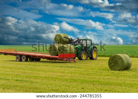 Tractor and trailer with hay bales in rural landscape