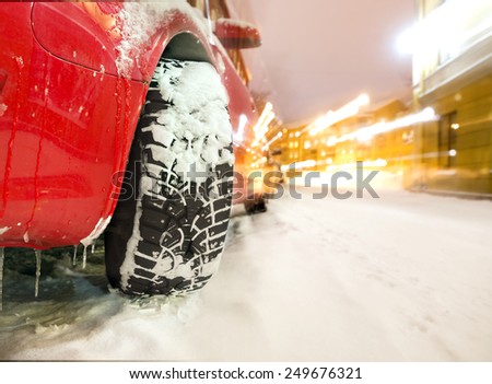 Studded tyre of red car on street in winter evening