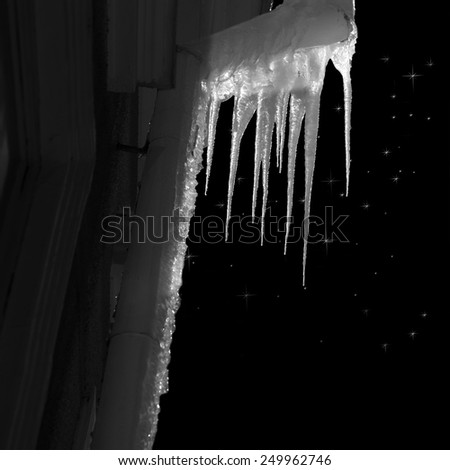 Icicles on pipe on facade of building on starry night