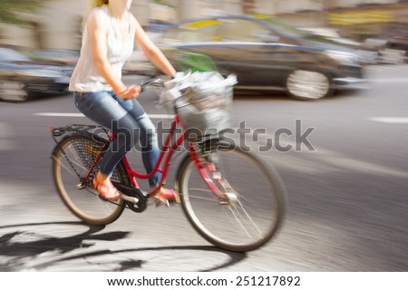 Woman on red bike in blurred motion on busy street