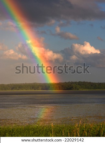 Rainbow over a lake, reflected in the water.