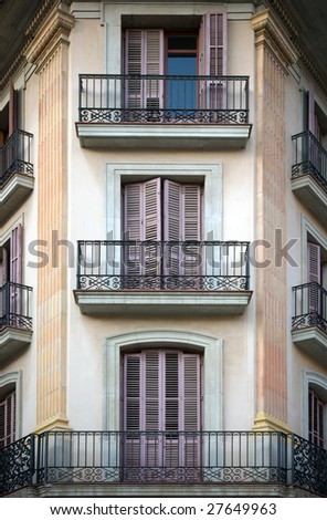 Spanish facade with balconies and doors painted in mauve color.