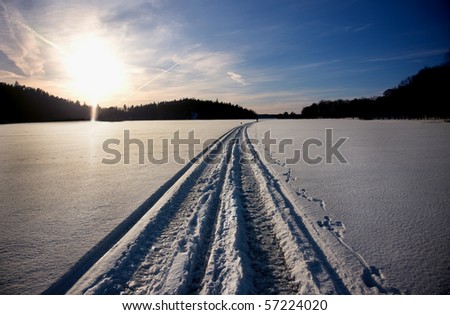 Track of snow mobile on the ice of a lake in winter