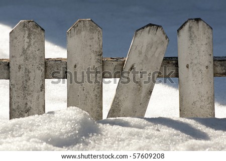 Old wooden fence in a snow drift on a sunny winter day