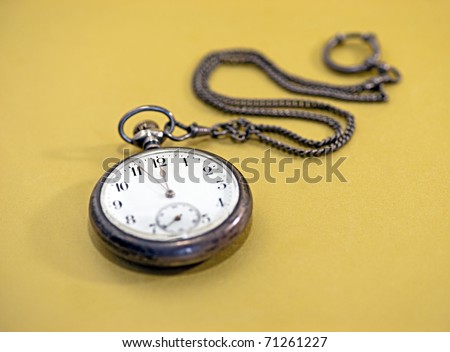 Close up of vintage pocket watch over golden background, focus on 12 o\'clock