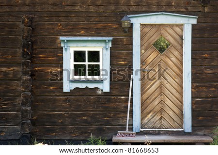 Facade of rural brown log cabin with door and window