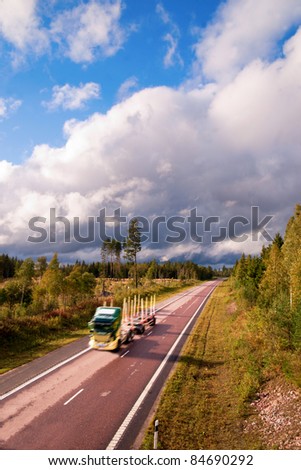 Empty timber truck in blurred motion with trailer on rural highway