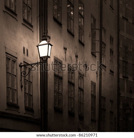 Facade of ancient sepia building with lantern at night