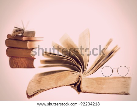 Open grunge vintage book isolated on white, with heap of books in background