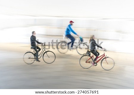 Three cyclists in blurred motion on smooth background