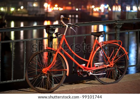 Orange bicycle on a bridge over a canal in Amsterdam
