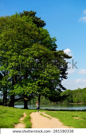 Green Landscape, Lake and Blue Sky in the Park . Little Girl running on the path. England, Uk