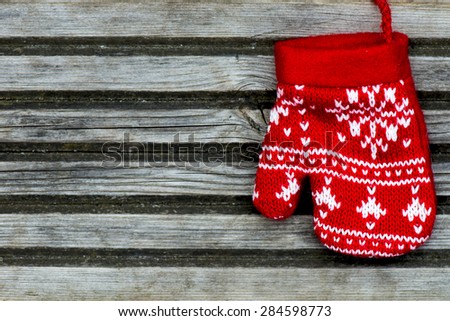 Christmas Red Knitted Mitten with Snowflake Motives on wooden background