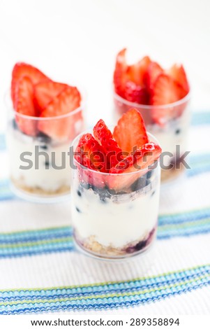 Delicious blueberries, strawberries, greek yogurt, agave syrup, flax seeds and granola parfaits on white background