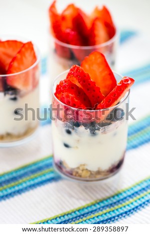 Delicious blueberries, strawberries, greek yogurt, agave syrup, flax seeds and granola parfaits on white background