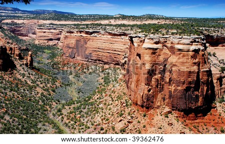 Red sandstone forms the side of a mesa in the US Southwest above a canyon
