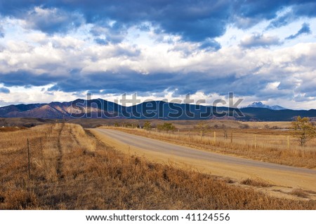 Rural road leads towards a distant patch of light on a mountain