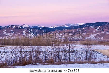 Pre-dawn pink alpenglow brushes mountains on the Colorado Continental Divide as seen from prairie fields near Boulder