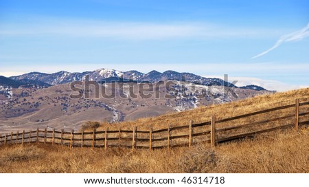 Simple fence on a hillside with view of distant mountains under a big blue sky with open spaces