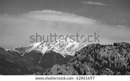 Distant snow capped mountain towers up, in black and white.