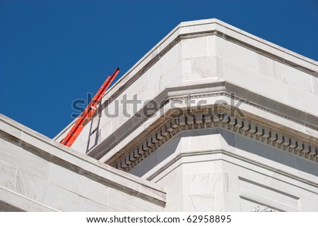 Bright orange ladder at the top of a public building appears to reach into the deep blue sky.