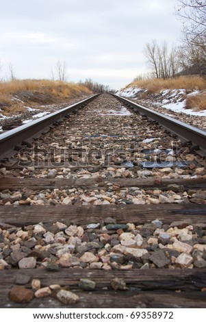 Converging train tracks from a low level looking up towards the horizon, with a light gravel bed between the rails.