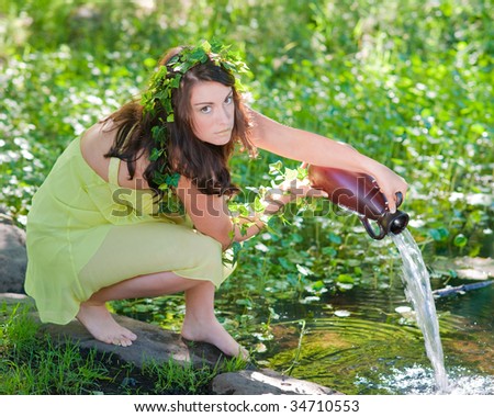 Beautiful girl in green organic makeup pouring water