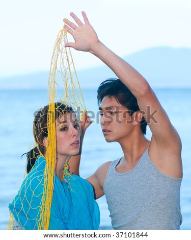 Young man lifting fishing net unveiling beautiful face of a girl