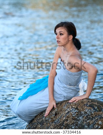 Young girl posing as water sprite on the rock