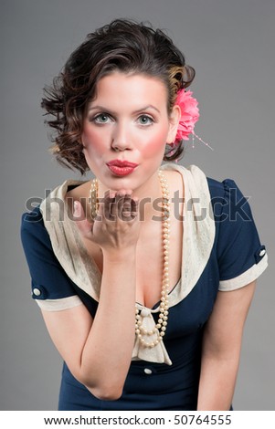 Beautiful young woman in a sailor girl pinup costume blowing a kiss