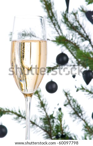 Sparkling wine in fluted champagne glass with christmas tree in out of focus background