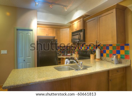 Contemporary kitchen with black appliances and granite backsplash