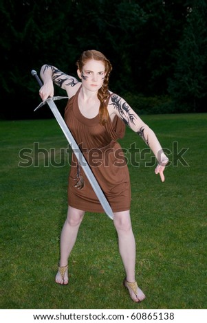 Beautiful redhead girl in celtic tribal makeup wielding a sword