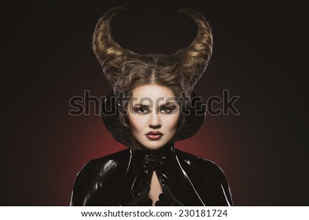 Girl with devil horns in a black pvc and leather shiny suit