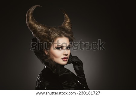 Girl with devil horns in a black pvc and leather shiny suit