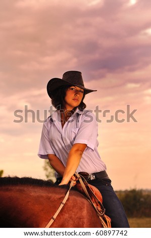Beautiful cowgirl with her horse on sunset