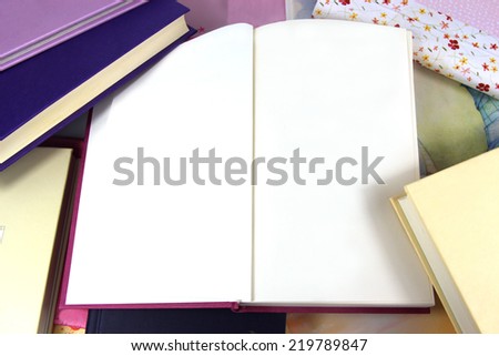 Blank pages in open book on background covered in books. Copy space.