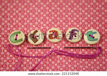 the word craft spelled in hand painted letters on buttons on a vibrant textile background.