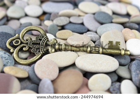 Old Brass key laying on beach stones on a pebble beach